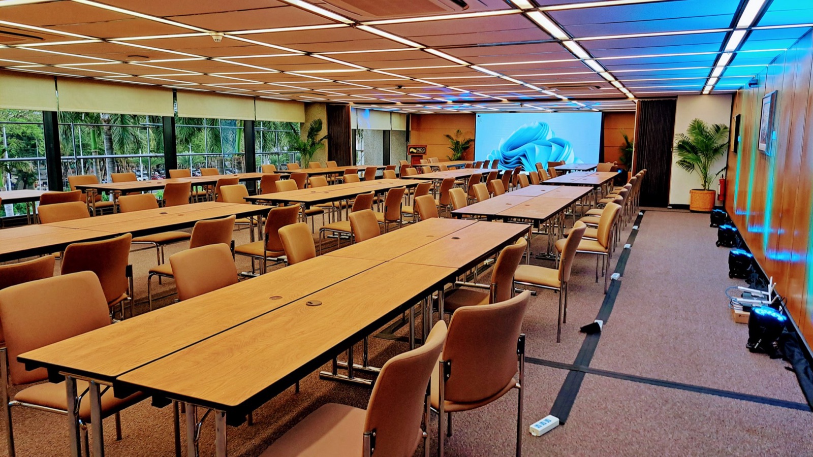 ห้องประชุมใหญ่จัดแบบคลาสรูม โต๊ะยาวหลายแถว หน้าต่างเต็มผนัง